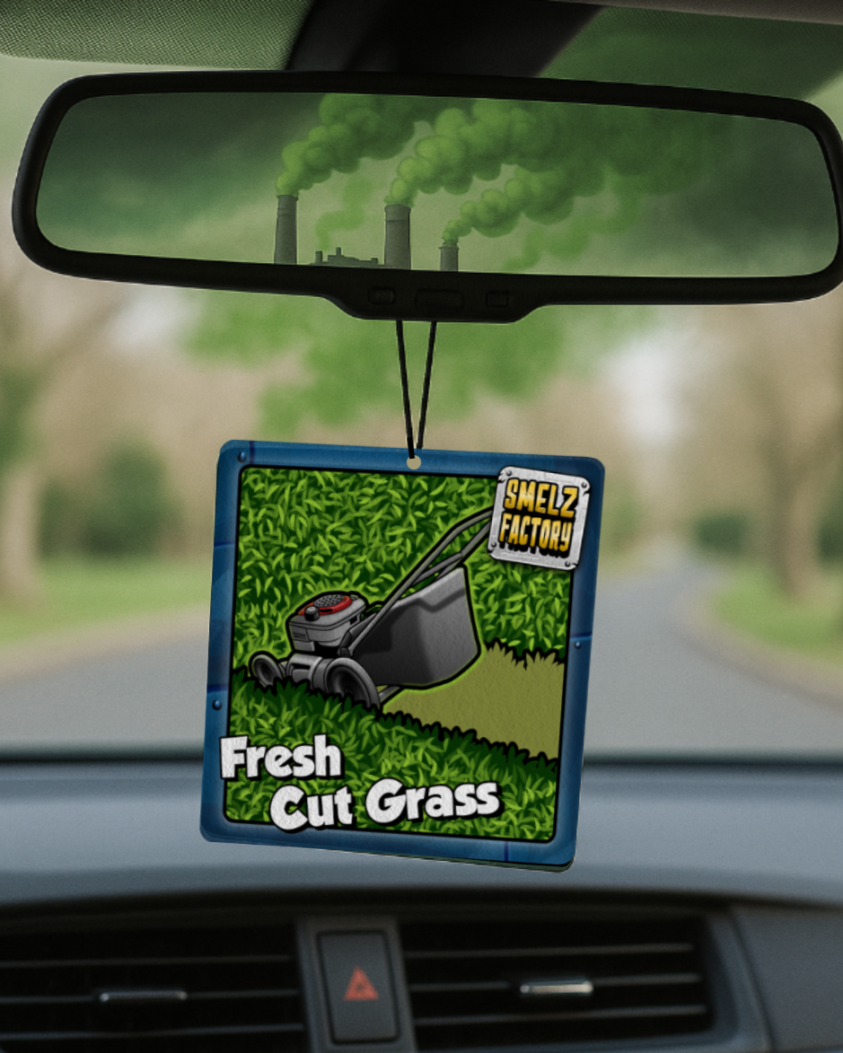 Car air freshener with 'Fresh Cut Grass' scent hanging from a car's rearview mirror.